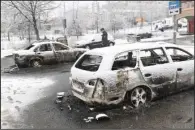  ?? AP/ CHRISTINE OLSSON ?? A Swedish policeman examines burned- out cars Tuesday in the Stockholm suburb of Rinkeby, where violence broke out.