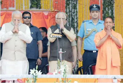  ?? — Reuters ?? Prime Minister Modi, Uttar Pradesh Governor Ram Naik (C) and Yogi Adityanath greet a gathering before Adityanath takes an oath as the new Chief Minister of Uttar Pradesh on Sunday.