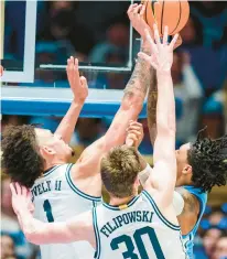  ?? JACOB KUPFERMAN/AP ?? Duke center Dereck Lively II (left) blocks a shot by North Carolina guard Caleb Love on Saturday night as the Blue Devils’ Kyle Filipowski defends.