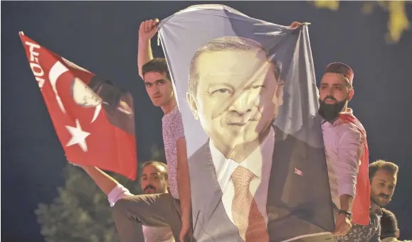  ?? Photo: AP ?? Men hold a banner with a picture of of Recep Tayyip Erdogan in Istanbul.