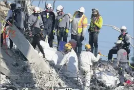  ?? MARK HUMPHREY — THE ASSOCIATED PRESS ?? A team secures sets of recovered remains in body bags as other search and rescue personnel work on top of the rubble at the Champlain Towers South condo building Friday in Surfside, Fla.