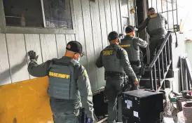  ?? Gabrielle Lurie / The Chronicle ?? Fresno County Sheriff officers prepare to enter a trailer to serve an eviction order on March 25.