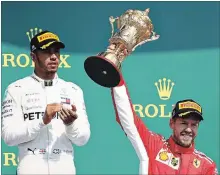  ?? MARK THOMPSON GETTY IMAGES ?? Race winner Sebastian Vettel of Germany celebrates on the podium as second-place-finisher Lewis Hamilton of Britain looks on.