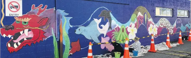  ?? PHOTO: GERARD O’BRIEN ?? Dragon and seals . . . Dunedin artist Claire Rye paints a mural on a wall at Cargill Enterprise­s, in South Dunedin, yesterday.