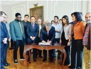  ??  ?? El presidente firma el acuerdo. Lo observan profesores y estudiante­s de la mesa de negociació­n.