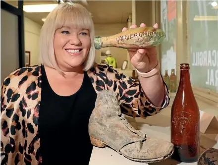  ?? ROBYN EDIE/STUFF ?? Invercargi­ll Central public relations manager Amy Hibbs holds a 19th-century Torpedo soda bottle, with an old boot and beer bottle in the foreground. The three items were among the latest artefacts returned to the city’s rebuild project company following archaeolog­y work on the CBD block area.