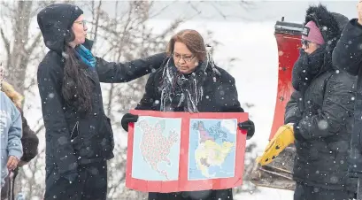  ?? LARS HAGBERG THE CANADIAN PRESS ?? Jocelyn Wabano-Lahtail holds two maps on the closed train tracks in Tyendinaga Mohawk Territory, near Belleville, on Thursday. The blockade is in solidarity with the Wet'suwet'en hereditary chiefs opposal to a liquid natural gas pipeline in British Columbia.