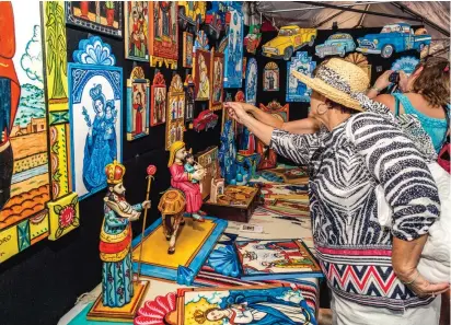  ?? PHOTO BY DANIEL QUAT ?? Visitors browse the booth of artist Charlie Carrillo at the 2014 Traditiona­l Spanish Market in Santa Fe.