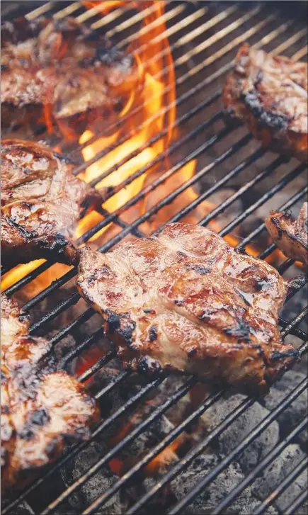  ?? MICHAEL GRAYDON & NIKOLE HERRIOTT / THE NEW YORK TIMES ?? Flames tickle pork shoulder steaks as they cook on a grill.