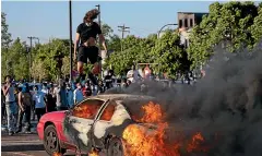  ?? AP ?? A car burns in a Target parking lot yesterday in Minneapoli­s. Minnesota Governor Tim Walz called in the National Guard as looting broke out in St Paul.