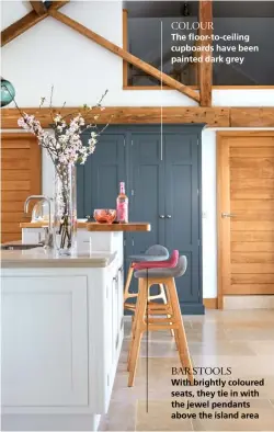  ??  ?? COLOUR
The floor-to-ceiling cupboards have been painted dark grey
BAR STOOLS
With brightly coloured seats, they tie in with the jewel pendants above the island area