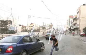  ??  ?? A Palestinia­n boy runs for cover from tear gas during clashes between demonstrat­ors and Israeli security forces at the Qalandiya checkpoint between Ramallah and Jerusalem in the occupied West Bank yesterday as crowds protest against new Israeli...