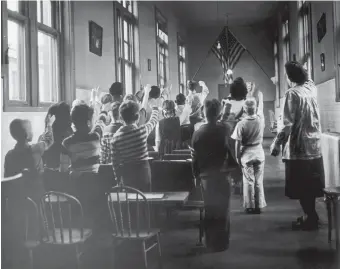  ??  ?? Children of immigrants pledging allegiance to the flag in a classroom on Ellis Island, 1940s