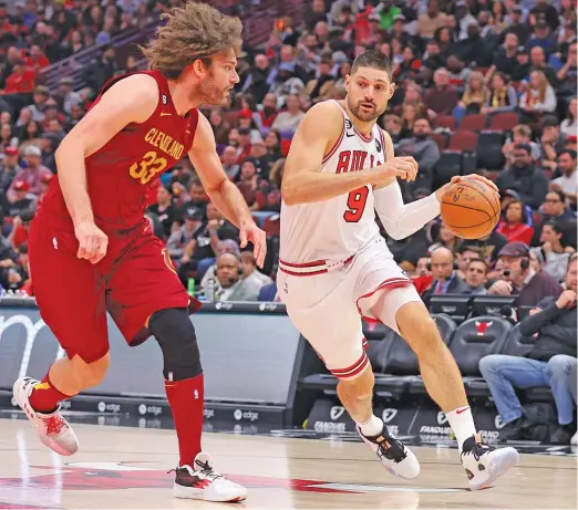  ?? MICHAEL REAVES/GETTY IMAGES ?? Bulls guard Goran Dragic says center Nikola Vucevic, driving to the basket against Cavaliers center Robin Lopez, receives unfair criticism.