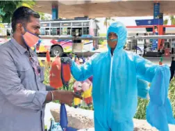  ??  ?? A STREET VENDOR wearing protective equipment gear selling face masks and PPE kits in Madurai on June 18.
