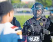  ??  ?? A Hobart, Indiana, police officer stands face-to-face with protesters during protests May 31 in Hobart.