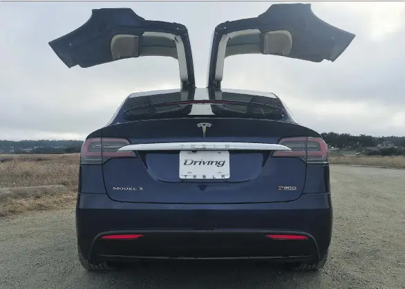  ?? PHOTOS: ANDREW MCCREDIE ?? With its falcon-wing doors deployed — they enable excellent access to both passengers and cargo — the battery-powered Tesla Model X looks poised for flight.