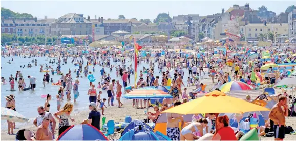  ??  ?? People flock to the beach at Weymouth, Dorset. Hospitals are reporting cases of fainting and collapses due to dehydratio­n.