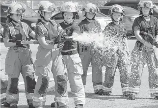  ?? WAYNE CUDDINGTON ?? Firefighte­r Claudia Cameron, third from left, offers instructio­n in firefighti­ng skills during Camp FFIT (Female Firefighte­rs in Training).