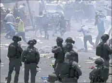  ??  ?? Palestinia­ns run from tear gas on Friday in Jerusalem.