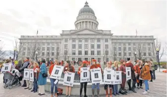  ?? RICK BOWMER, AP ?? Women in red hold signs with photos of their lawmakers Wednesday at the Utah Capitol in Salt Lake City to remind legislator­s they’re closely watching how they handle women’s issues.