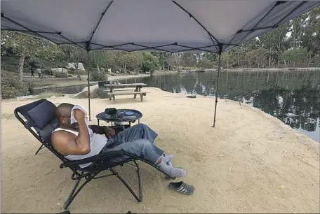  ?? Genaro Molina Los Angeles Times ?? ALONZO FRAZI tries to keep cool under a canopy while fishing Friday, during the heat wave, at Kenneth Hahn State Recreation Area.