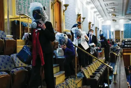  ?? Andrew Harnik / Associated Press ?? People wearing protective headgear in the event gas is unleashed shelter in the House gallery as a mob attempts to break in.