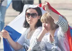  ?? People shelter from the sun under the French flag at a vigil for the victims of the Paris terrorist strikes in Melbourne yesterday after 132 died in a series of blasts.
AFP ??