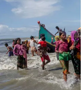  ??  ?? EXODUS: Refugee Rohingya Muslims walk to shore after fleeing from Myanmar to Bangladesh. Photo: Dar Yasin/AP