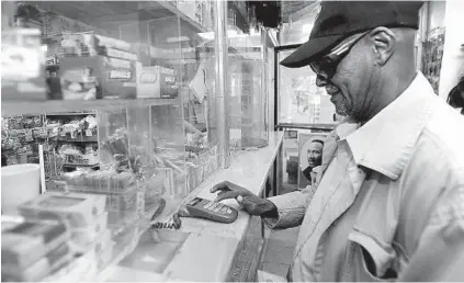  ?? BARBARA HADDOCK TAYLOR/BALTIMORE SUN PHOTOS ?? James Gaymon uses a PIN pad to make a purchase with food stamps at the A to Z convenienc­e store on Park Heights Avenue.