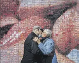  ?? MANU MITRU ?? Un matrimonio se besa ante un mural dedicado al beso.