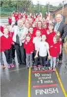  ??  ?? > Pantysgall­og Primary’s Morning Mile is improving children’s performanc­e in the classroom in Merthyr Tydfil. Pictured are Public Health Minister Rebecca Evans, PE co-ordinator Rebecca Rogers and headteache­r Darren Thomas, with pupils from the school