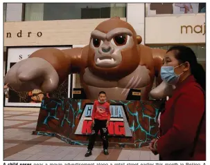  ?? (AP/Ng Han Guan) ?? A child poses near a movie advertisem­ent along a retail street earlier this month in Beijing. A recovery in factory and consumer activity buoyed China’s economic growth in the first quarter of the year.