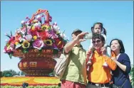  ?? WANG ZHUANGFEI / CHINA DAILY ?? Tourists take photos with the flower display in Tian’anmen Square to celebrate National Day.