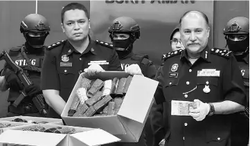  ??  ?? Mokhtar (right) along with his officers show a box of the seized Erimin 5 pills. — Bernama photo