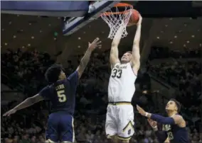  ?? THE ASSOCIATED PRESS ?? Notre Dame’s John Mooney (33) dunks the ball between Pittsburgh’s Marcus Carr (5) and Shamiel Stevenson (23) during the second half of an NCAA college basketball game Wednesday in South Bend, Ind. Notre Dame won 73-56.