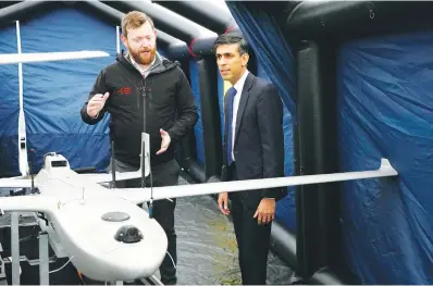  ?? (AP Photo/ Kirsty Wiggleswor­th, Pool) ?? Britain’s Prime Minister Rishi Sunak, right, speaks with a member of the Home Office contracted staff as he views a drone used for surveillan­ce of vessels in distress during a visit Tuesday to a Home Office joint control room in Dover, Kent, England.