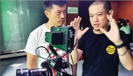  ?? PROVIDED TO CHINA DAILY ?? Hsueh Ying-tung, a movie director from Tainan, Taiwan, discusses shooting techniques with a colleague in Wuhan, Hubei province.