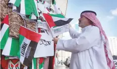  ?? Abdul Rahman/Gulf News ?? Abu Mohammad, a resident, selects a UAE flag at a shop in the Abu Dhabi Souq yesterday.