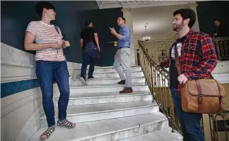  ?? AP Photo/Charles Krupa ?? ■ Zak Ringelstei­n, center, a Democratic candidate for U.S. Senate in Maine, talks with a passerby while climbing the stairs inside City Hall to attend a meeting of the Southern Maine Democratic Socialists of America on Monday in Portland, Maine.