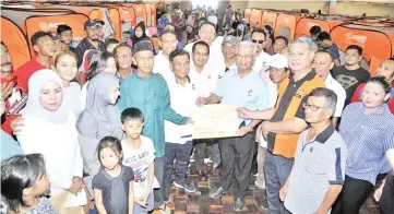  ??  ?? Uda (third from right) handing over the donation to a representa­tive of the fire victims.