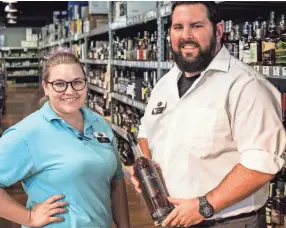  ??  ?? Angie Adams, left, assistant manager, and Ryan Gill, general manager, show off a bottle of the first edition of Doc’s Wine, spirits and More’s Doc. 52. Doc’s Wine, spirits and More will start selling the 179 bottles of its own store-brand bourbon on Saturday.