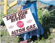  ??  ?? Mi’kmaq activist Ducie Howe carries a sign at an encampment near the Shubenacad­ie River in Nova Scotia.