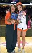  ?? ARCENIO J. TRUJILLO/Taos News ?? Coach Lisa Abeyta-Valerio stands proudly with her daughter, Feliz — shown wearing all four of her individual medals she’s won since being on the Taos cheer roster — and the newly-acquired trophy at the UNM Pit April 6.
