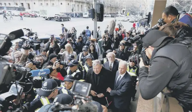  ??  ?? 0 Cardinal George Pell walks with a heavy Police guard to the Melbourne Magistrate­s’ Court to face charges of sex abuse