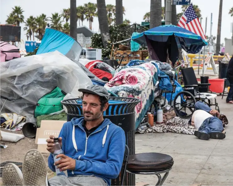  ??  ?? Joseph Frye, 35 år og fra West Virginia, er en af de mange hjemløse på strandprom­enaden i Venice Beach, Californie­n. Han tjener penge ved at spille musik og lider ingen nød, siger han. Mange butiksejer­e og boligejere er trætte af rodet, larmen og den kriminalit­et, som tilstrømni­ngen har ført med sig.