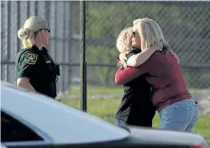  ?? JOE RAEDLE/ GETTY IMAGES ?? Assistant principle Denise Reed, right, hugs a school employee as she arrives at Marjory Stoneman Douglas High School in Parkland, Fla., on Friday.
