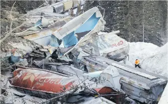  ?? JEFF McINTOSH, CANADIAN PRESS ?? A worker inspects the damage after a train derailment near Field on Monday.