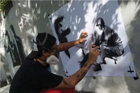  ?? - AFP ?? GAMBAR yang dirakam pada 4 September lalu, menunjukka­n artis grafiti Thailand, ‘Headache Stencil’ melukis karikatur pada tembok pagar di Bangkok.
