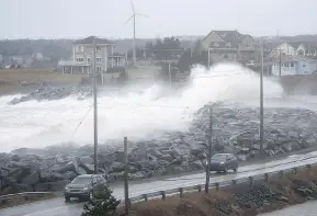  ?? SANDOR FIZLI PHOTO FOR THE NATIONAL POST ?? Vehicles in Cow Bay, N.S., get sprayed with water as waves crash against a seawall, following a night of heavy winds from a “weather bomb” that hit the East Coast.